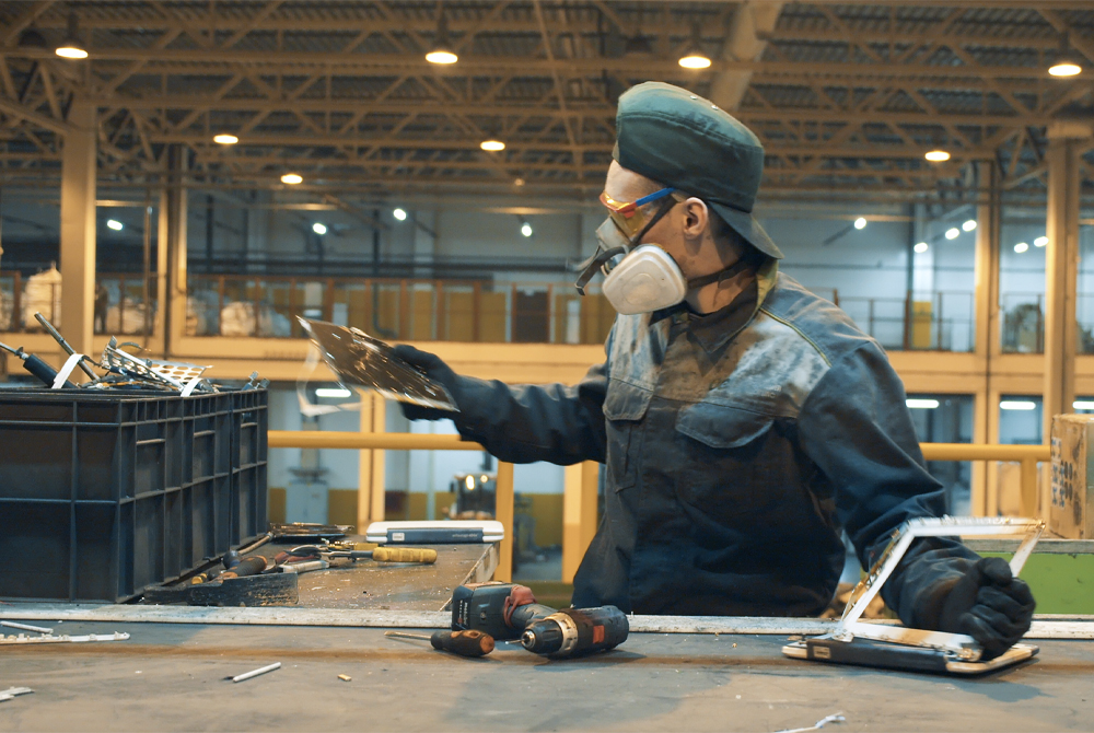 A man processing parts while wearing safety equipment